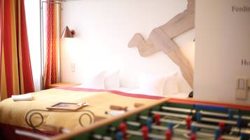 A hotel room with a bed, a foosball table, and a wall-mounted artwork.