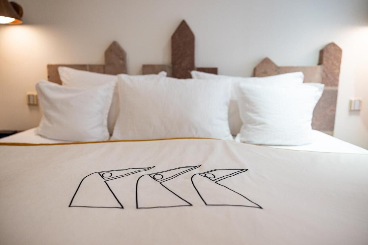 A neatly made bed with white bedding and a geometric design on the duvet cover.