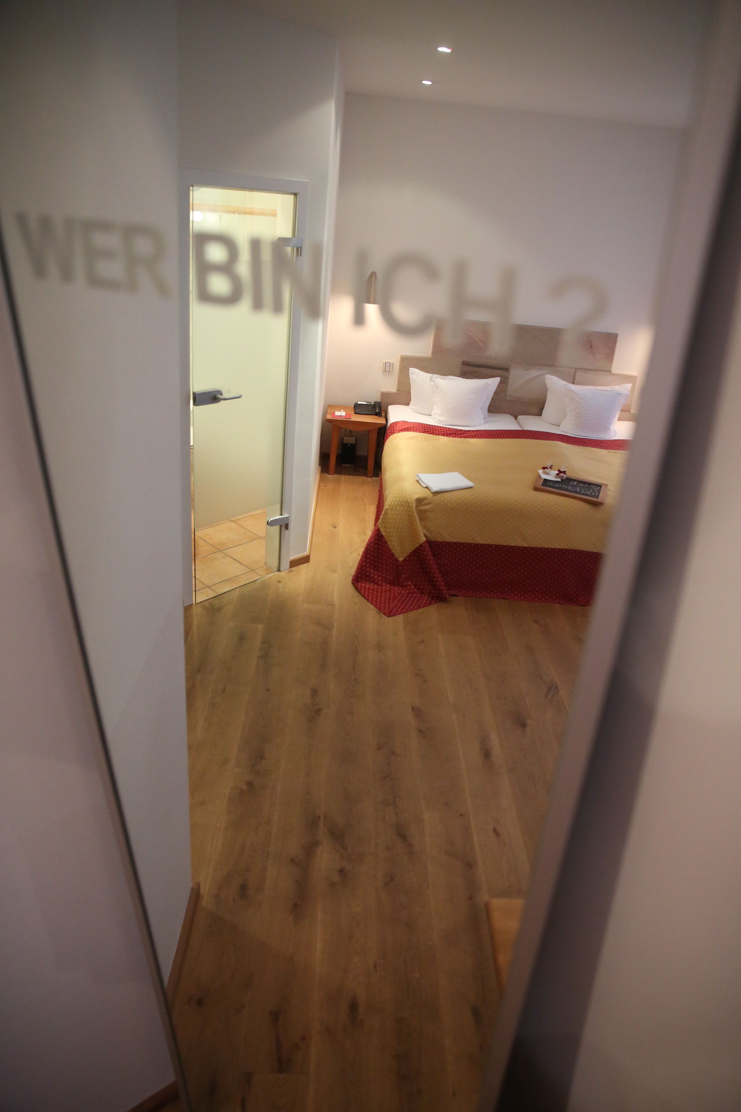 Ein Hotelzimmer mit einem Bett, einem Nachttisch und einer Tür zu einem weiteren Raum.