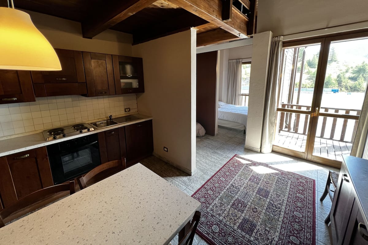 A kitchen with wooden cabinets, a stove, and a dining area with a table and chairs.