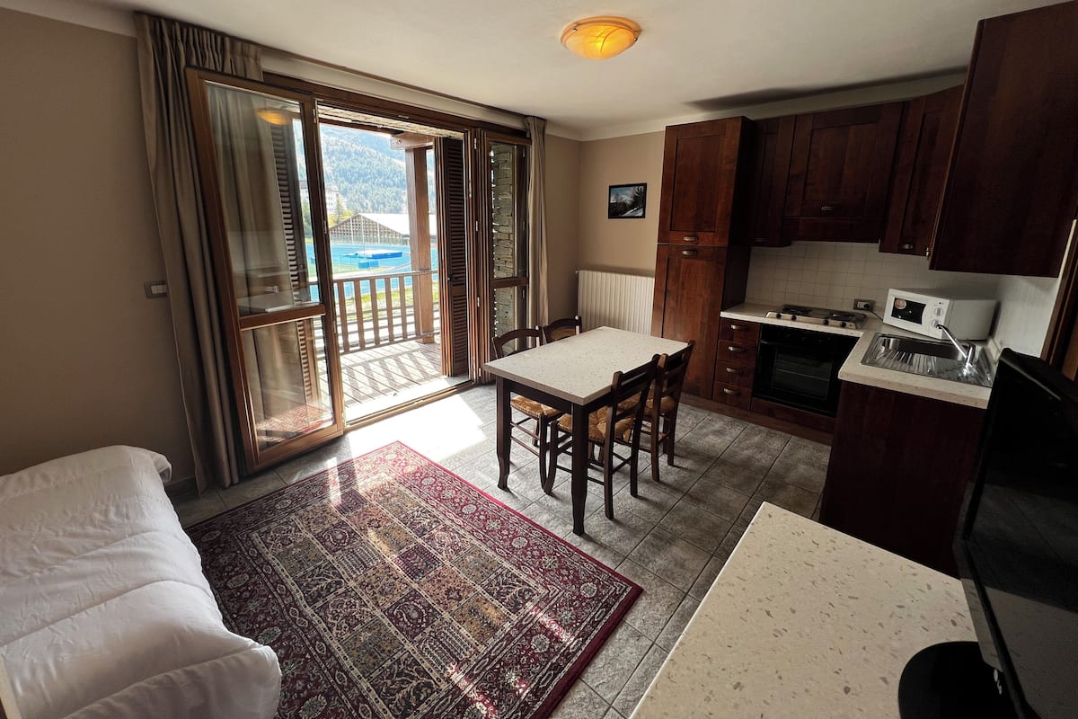 A compact kitchen with a dining area, a view through the sliding glass door, and a small dining table.
