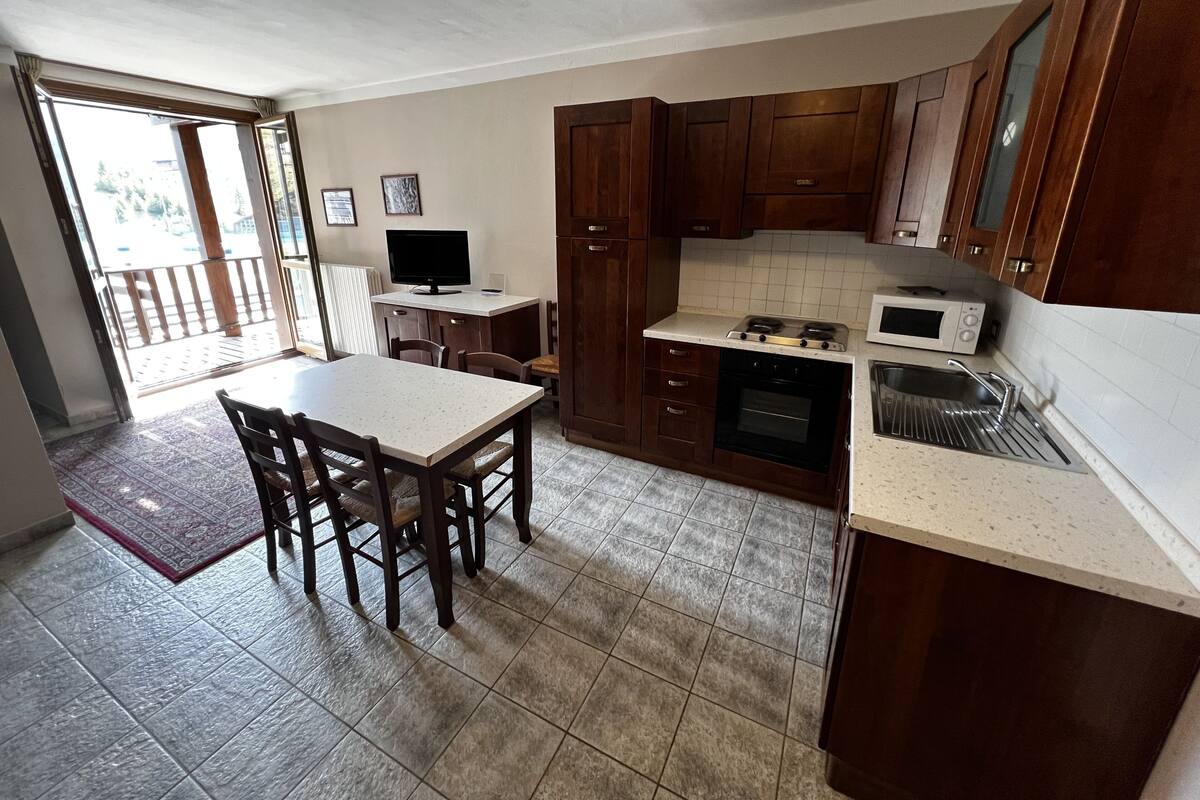 A kitchen with a dining table, chairs, a stove, microwave, and cabinets.