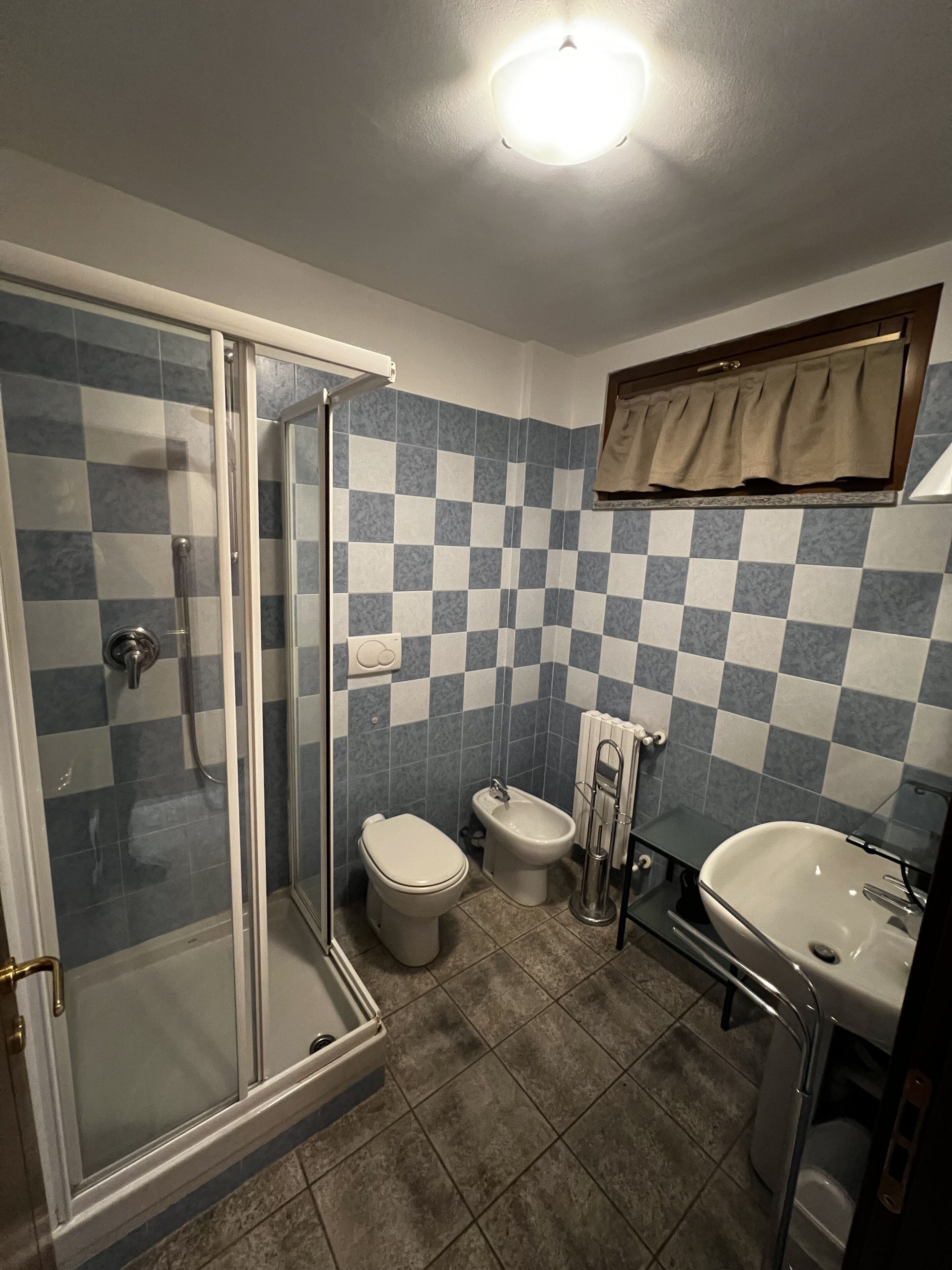 A bathroom with a glass shower enclosure, a toilet, a bidet, and a sink.