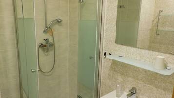 Un baño con cabina de ducha de vidrio, lavamanos y espejo.