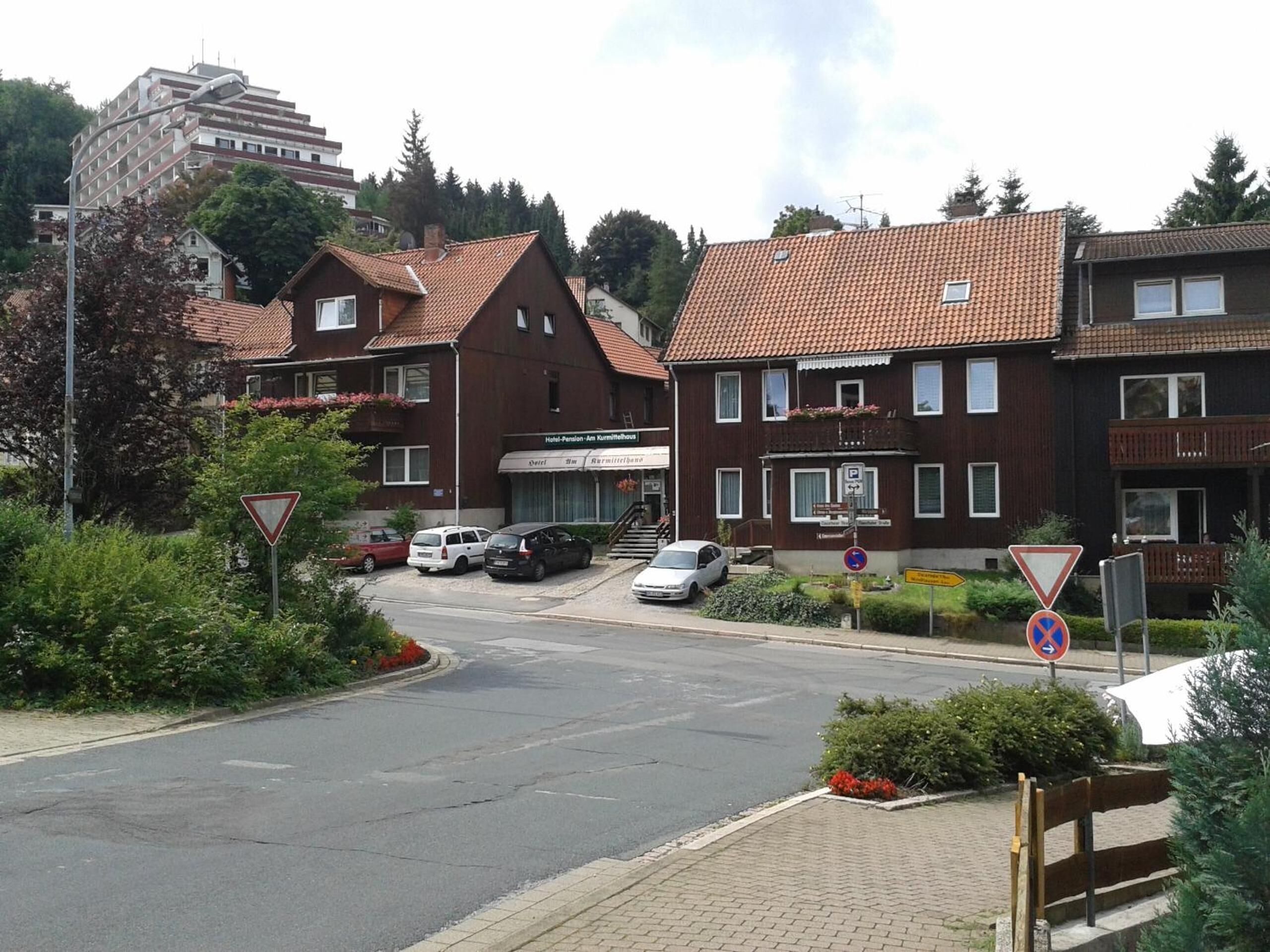 A street view with a hotel named "Hotel Pension Am Kummitalhaus" and a building with a red-tiled roof.