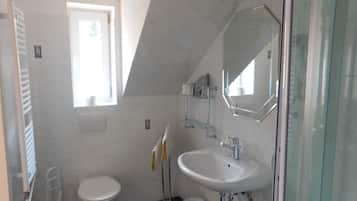 Ein modernes Badezimmer mit Toilette, Waschbecken und Duschbereich.