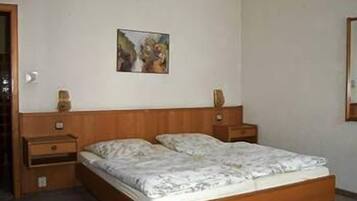 Quarto com estrutura de cama de madeira, mesa de cabeceira com abajur e um quadro na parede.