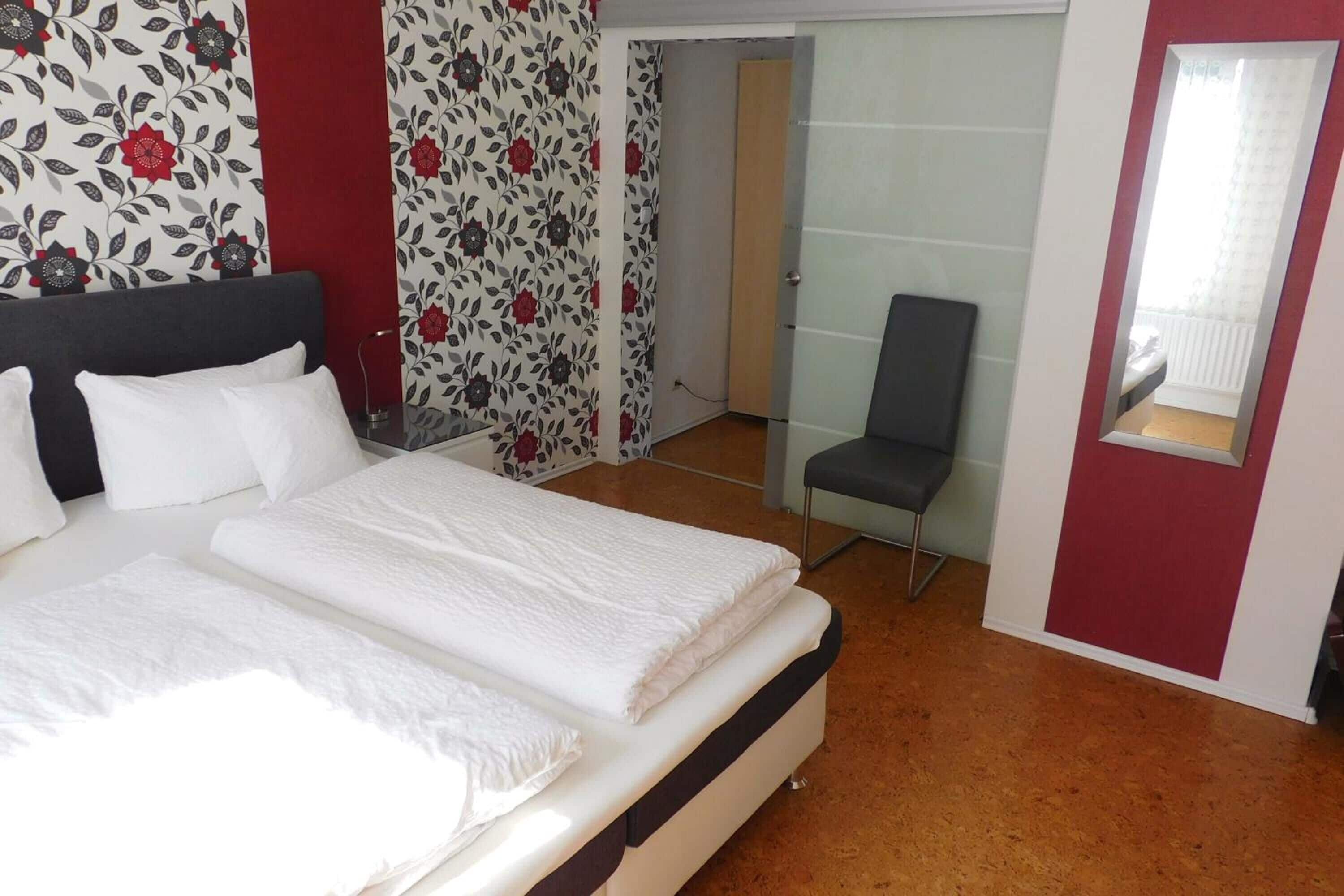 Un dormitorio con cama, una silla y un espejo.