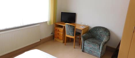 A bedroom with a bed, a desk with a computer, a chair, and a wardrobe.