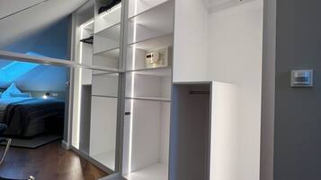 Ein modernes Schlafzimmer mit begehbarem Kleiderschrank, einem Bett und einem Sessel.