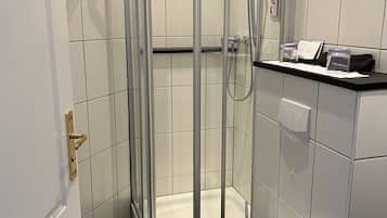 A modern bathroom with a glass-enclosed shower, a toilet, and a sink with a towel rack.