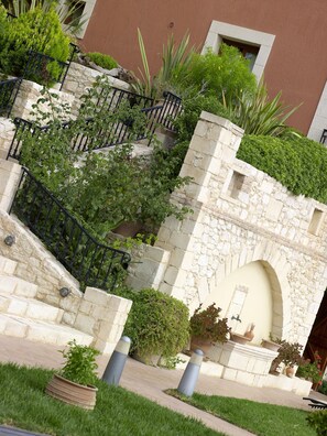 A stone staircase with a metal railing, surrounded by lush greenery and potted plants. - Katalagari Country Suites (Archanes-Asterousia)