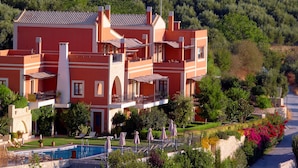 A large, multi-story building with a swimming pool, outdoor seating, and lush landscaping. - Katalagari Country Suites (Archanes-Asterousia)