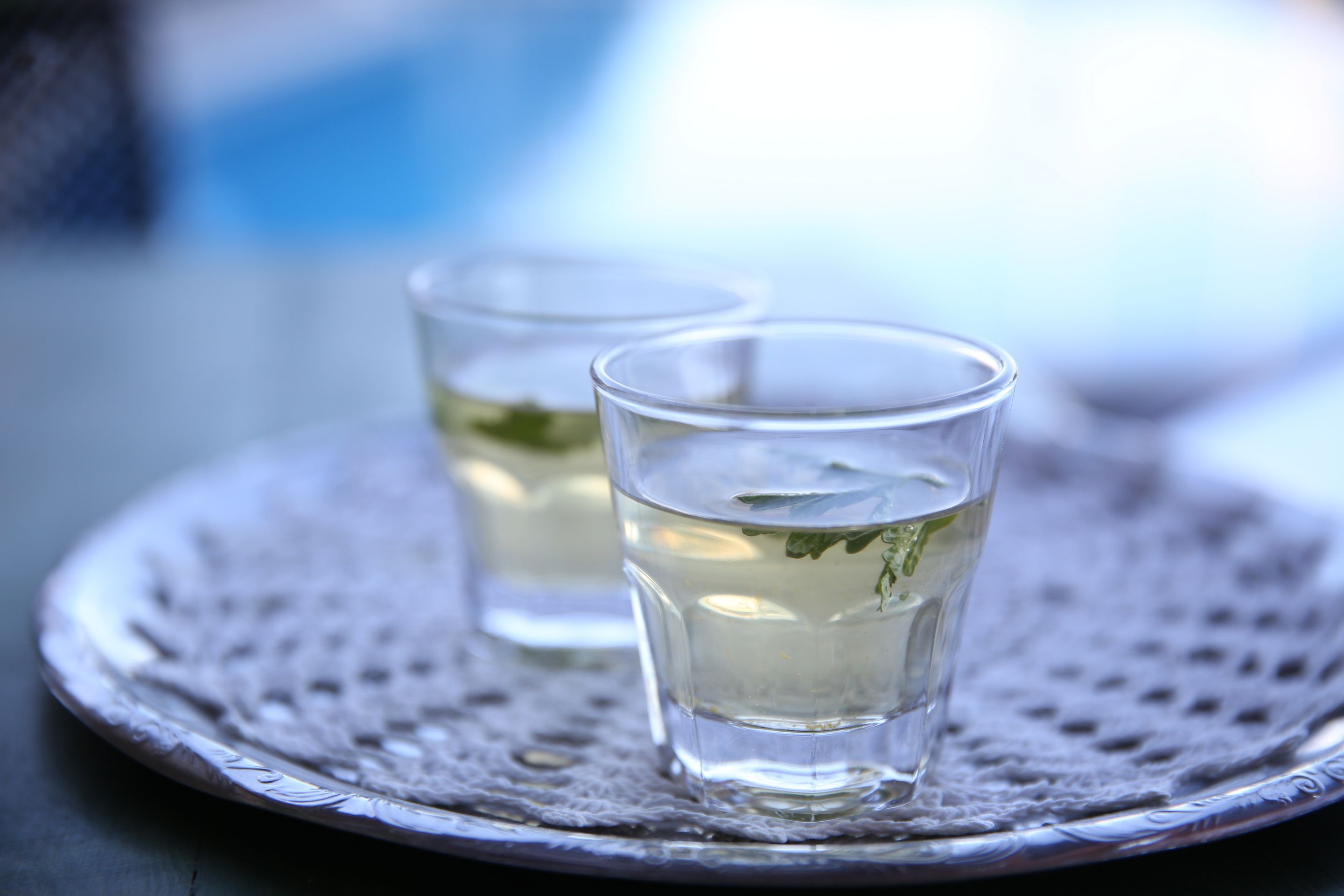 Two clear glasses of water on a silver tray with a textured surface.