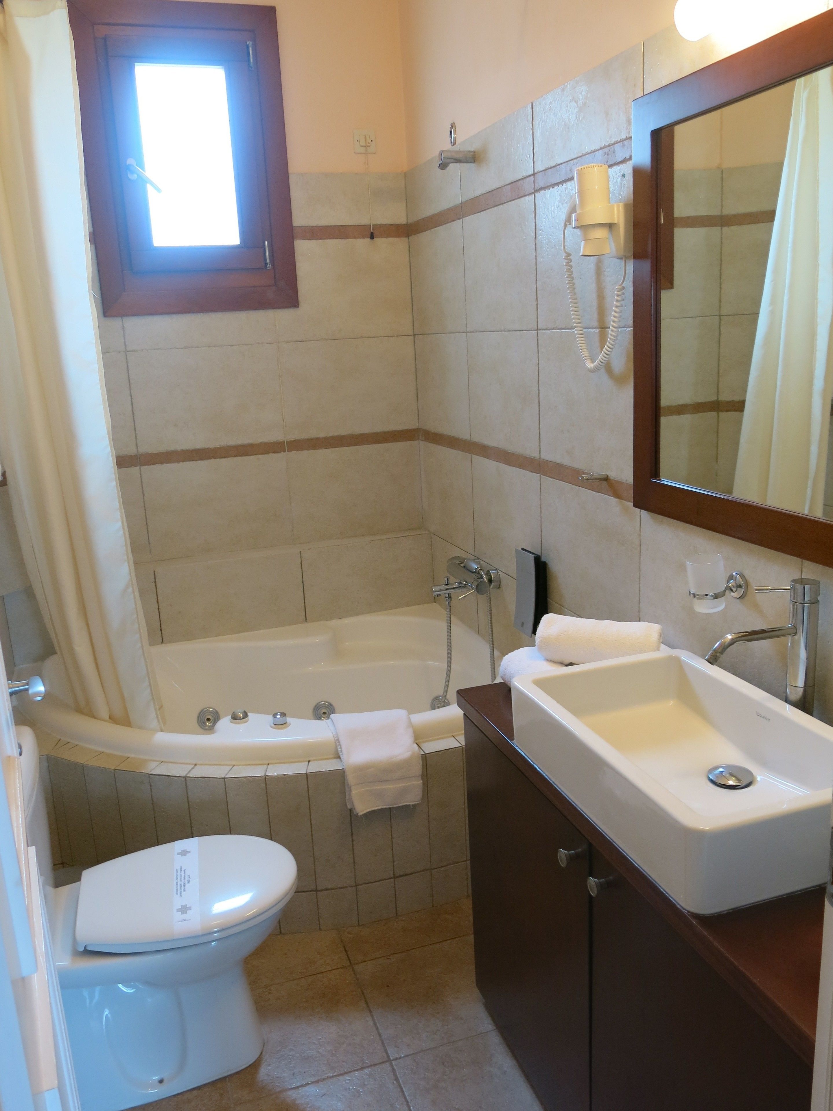 A bathroom with a bathtub, a toilet, a sink, and a mirror.