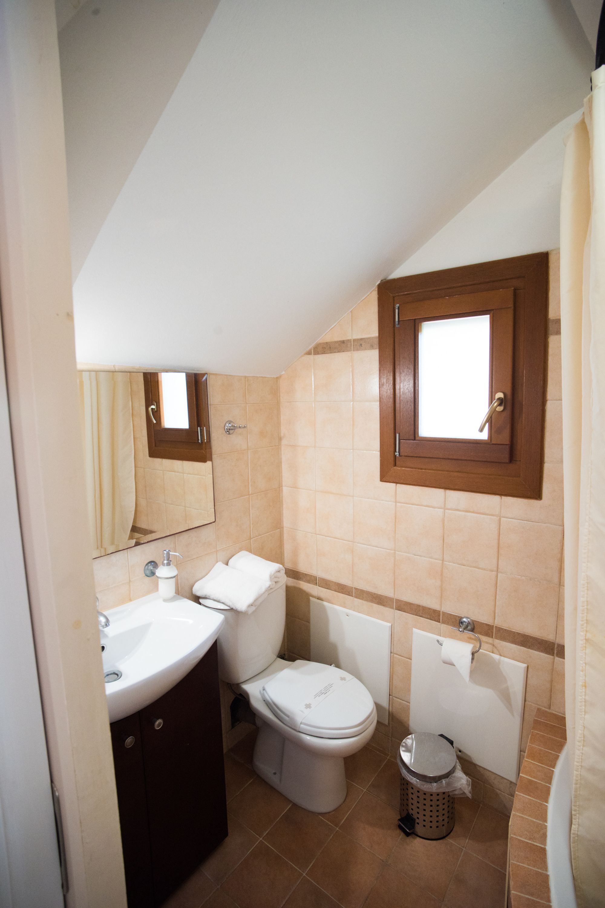 A bathroom with a toilet, sink, and mirror.