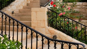 A stone staircase with black railings leading to a door, surrounded by greenery and flowers. - Katalagari Country Suites (Archanes-Asterousia)