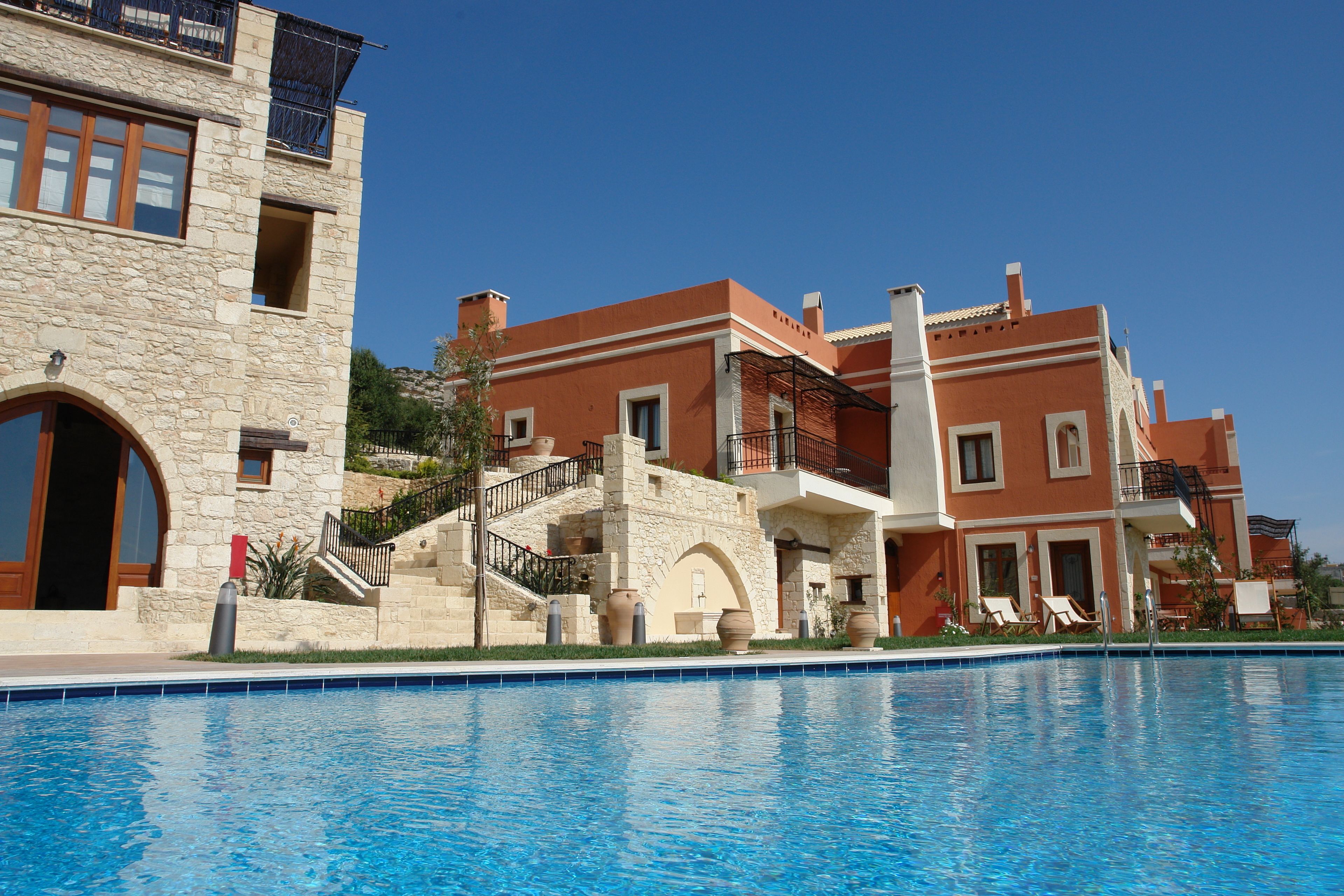 A hotel with a pool, stone facade, and multiple balconies.