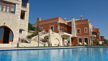 A hotel with a pool, stone facade, and multiple balconies.