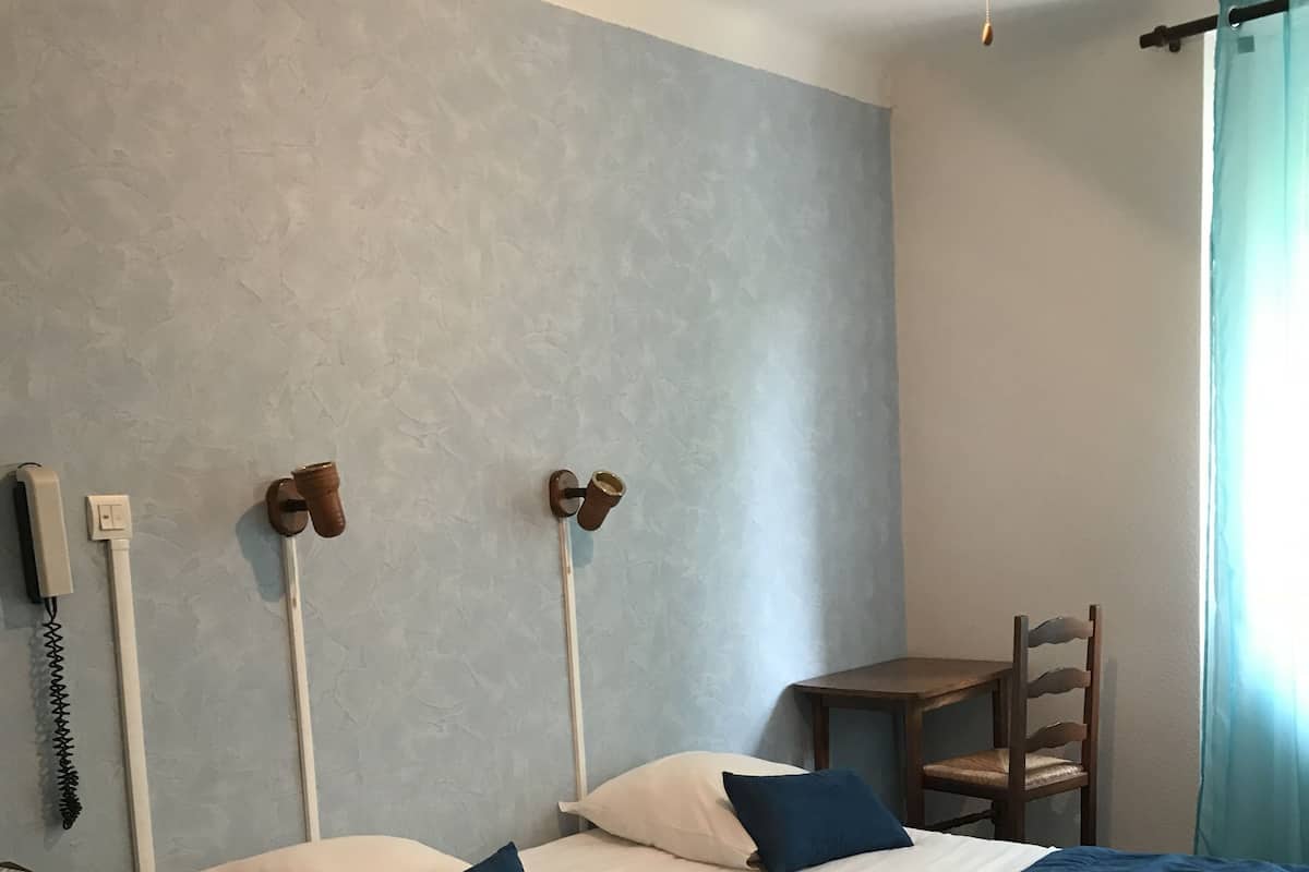 Makuuhuoneessa on sänky, yöpöytä, tuoli ja seinälle kiinnitetty puhelin.