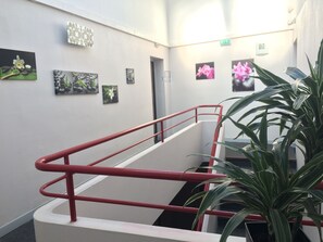 A staircase with red railings, a potted plant, and artwork on the walls. - Au Royal Hôtel (Carcassonne)