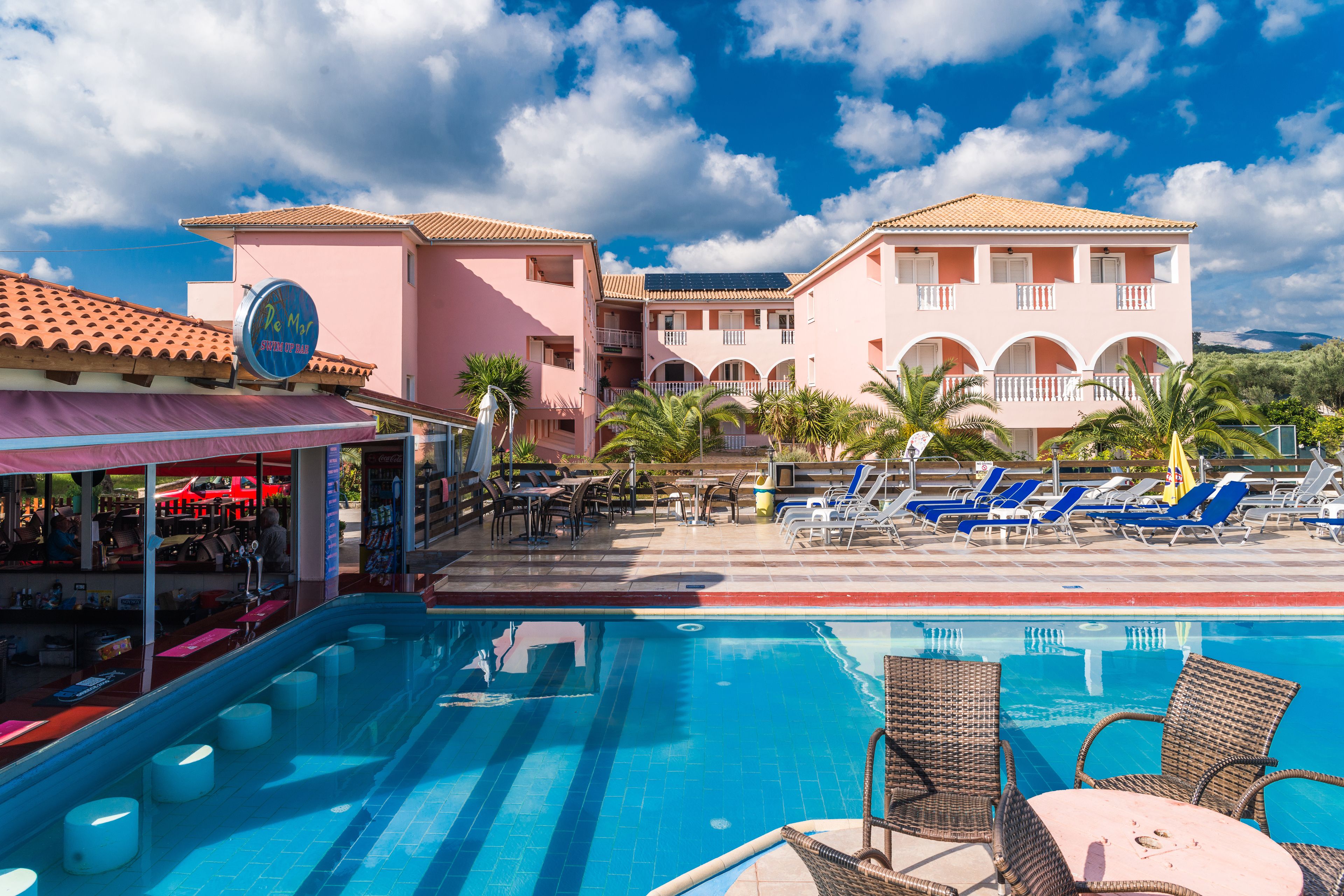 A hotel with a swimming pool, outdoor seating, and a bar.