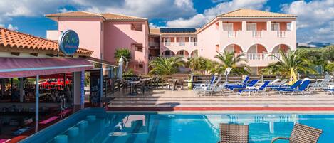 A hotel with a swimming pool, outdoor seating, and a bar.