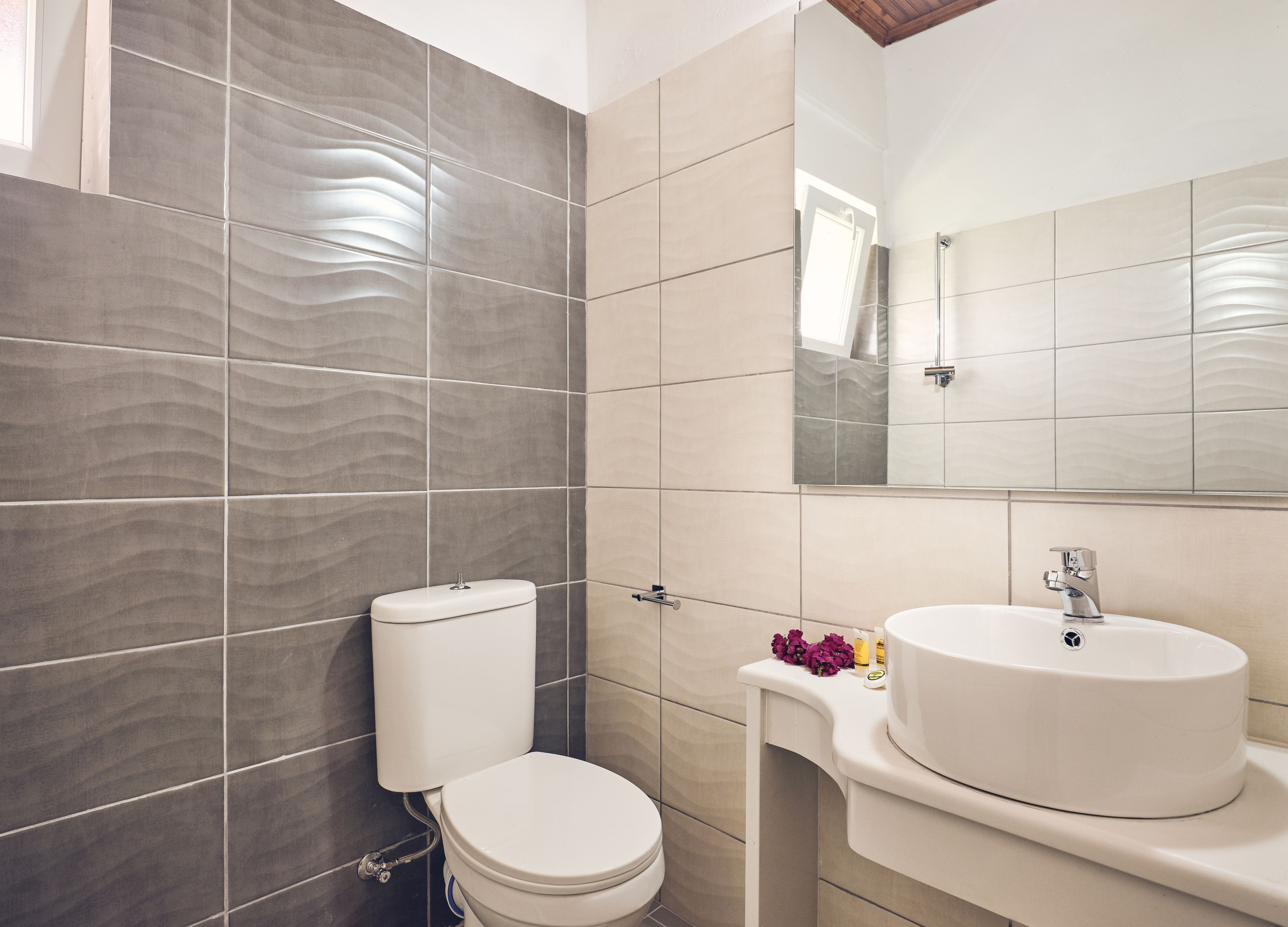 Un baño moderno con inodoro, lavabo y espejo.
