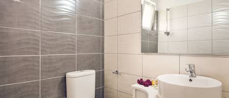 Un baño moderno con inodoro, lavabo y espejo.