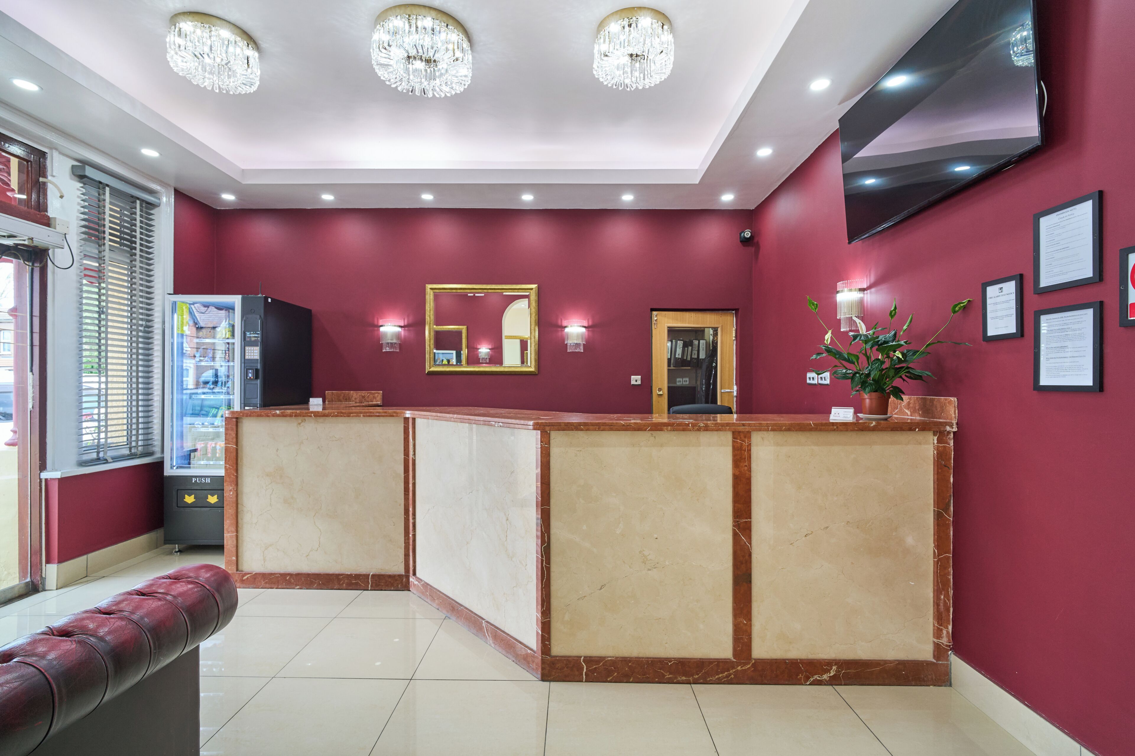 A reception area with a marble counter, a television, and a vending machine.