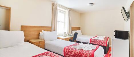 Une chambre d’hôtel avec deux lits, un bureau, une chaise, une télévision et un four à micro-ondes.