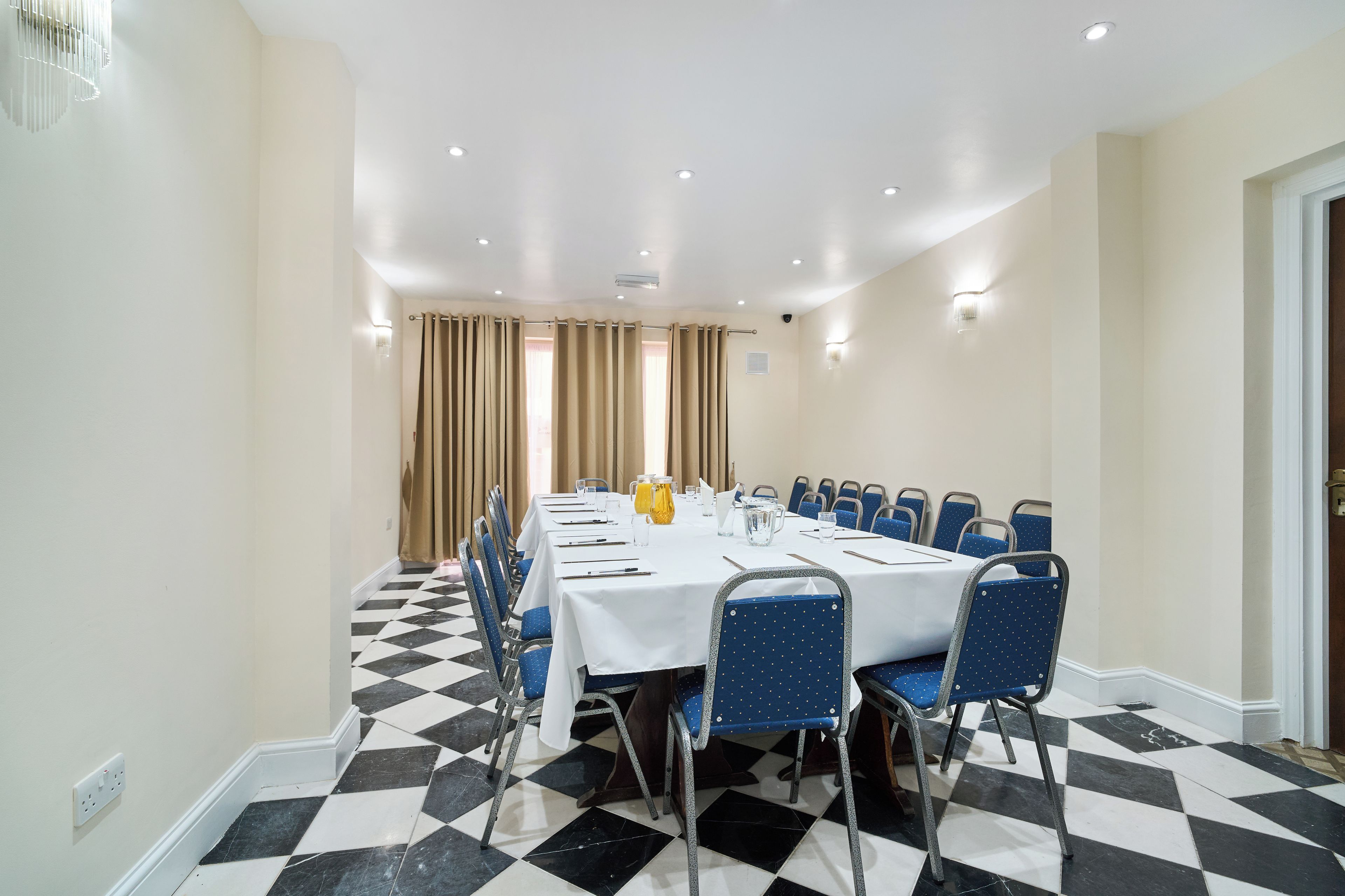 A conference room with a long table, chairs, and a checkered floor.
