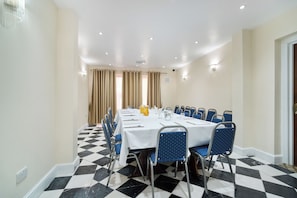 Une salle de conférence avec une longue table, des chaises et un sol à carreaux.