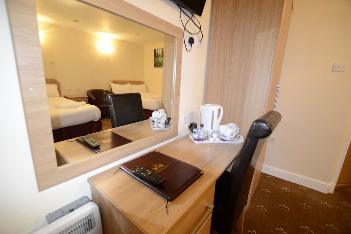 Una habitación de hotel con un escritorio de madera, un espejo, una cama, una silla y una cafetera.
