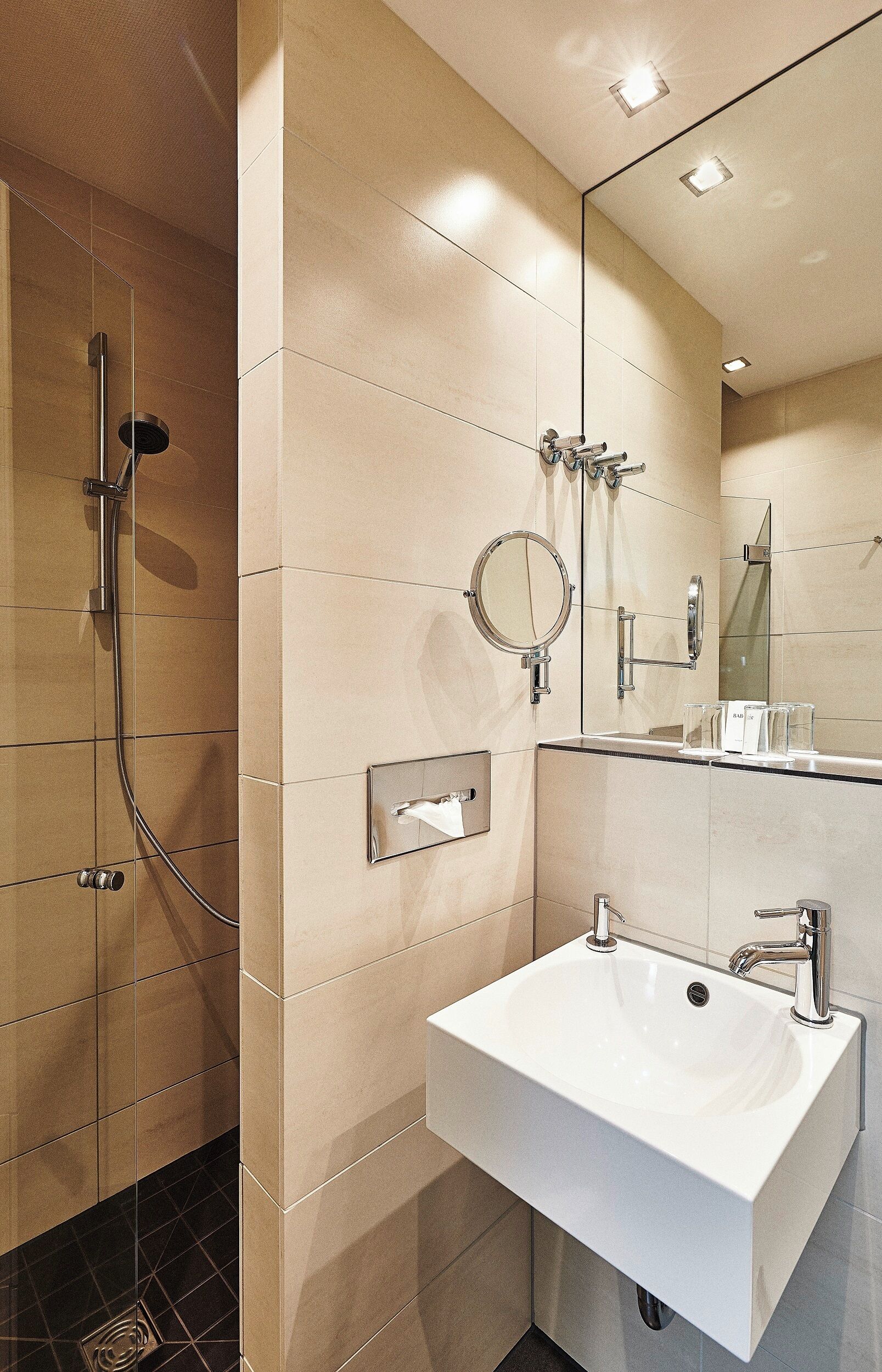 Une salle de bain moderne équipée d’une douche, d’un lavabo et d’un miroir.
