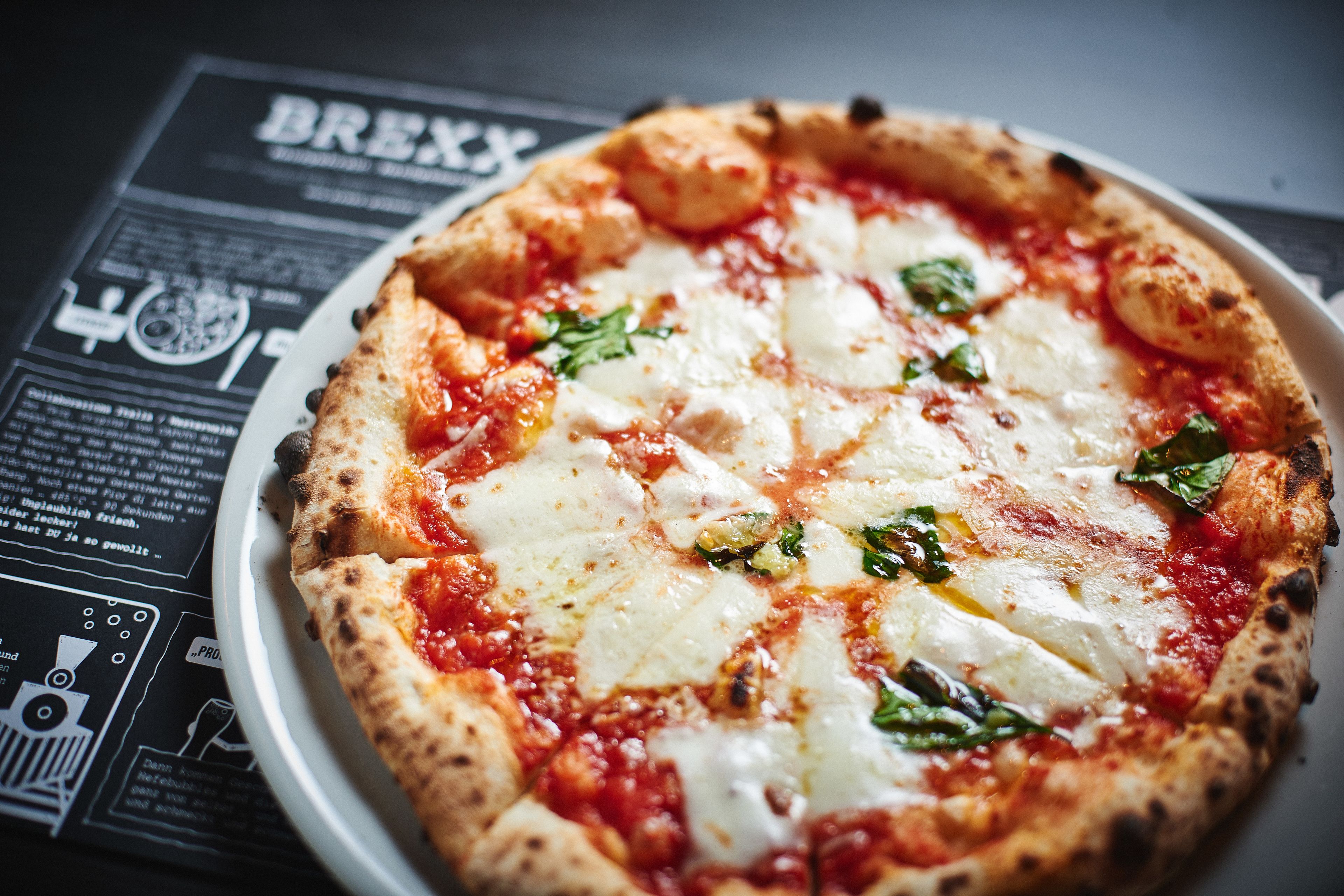 A pizza on a white plate with a menu underneath.