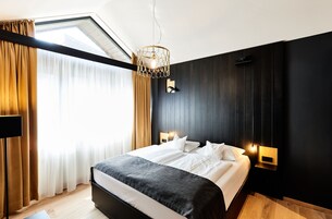 Un dormitorio moderno con una cama grande, una lámpara de techo y una mesita de noche.