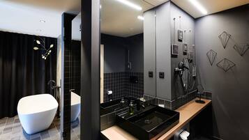 Un baño moderno con una bañera independiente, un tocador con un lavabo negro y un espejo.