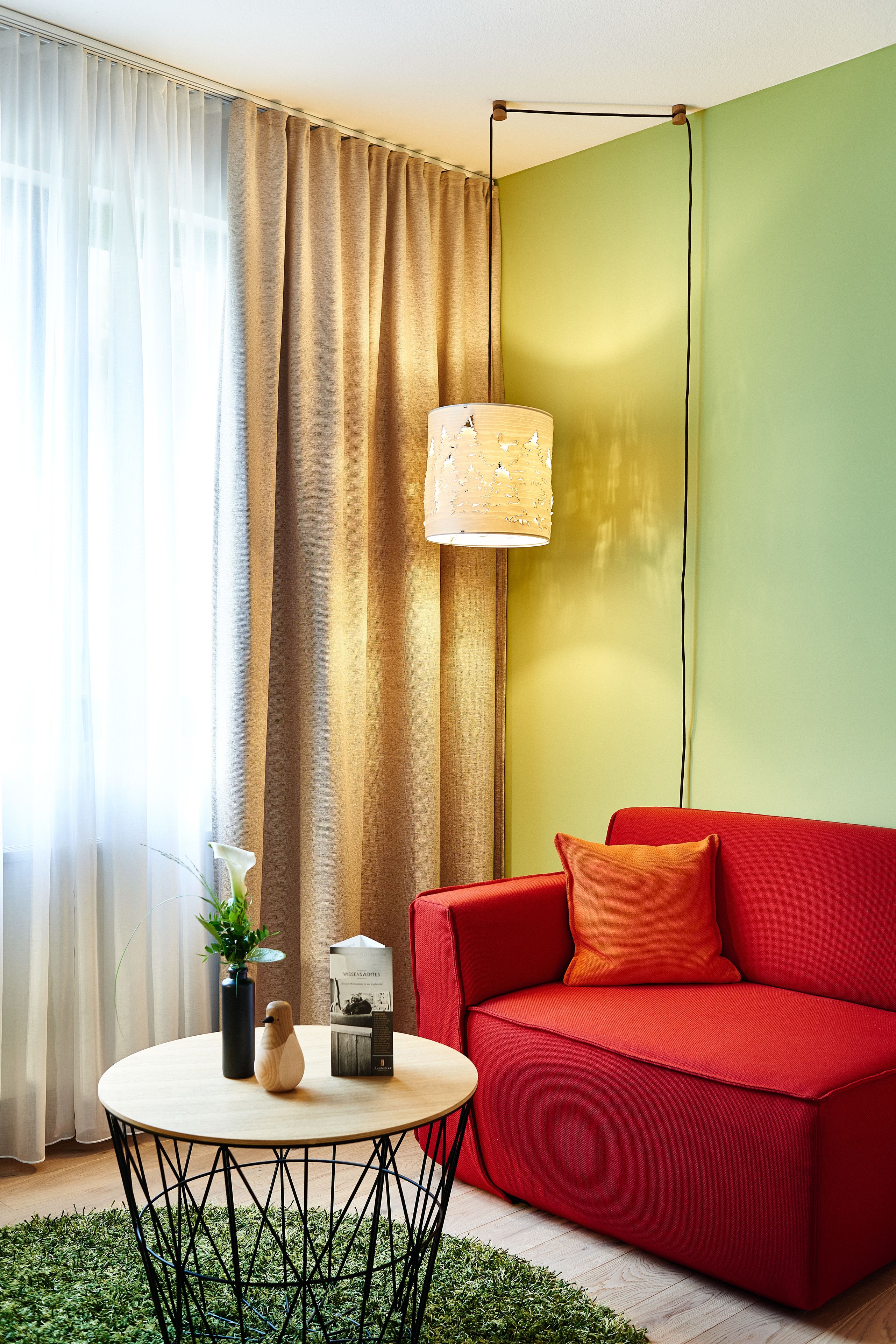 Una sala moderna con un sofá rojo, una mesa de centro redonda y una lámpara.