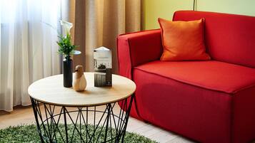 Una sala moderna con un sofá rojo, una mesa de centro redonda y una lámpara.