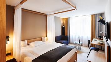 Una habitación de hotel con una cama grande, un escritorio con una silla, una mesita y un televisor.