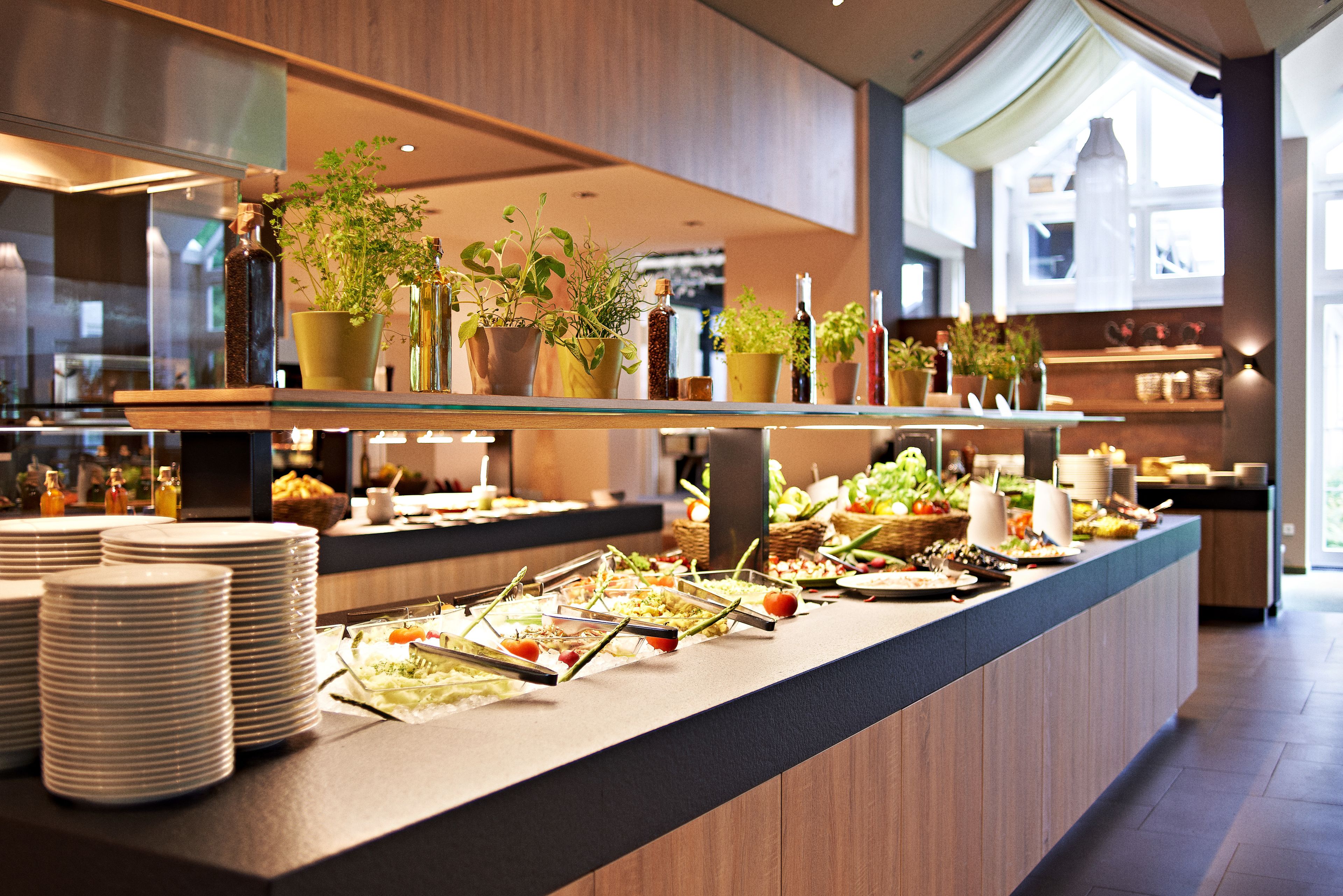 Ein reichhaltiges Buffet mit verschiedenen Speisen, Tellern und Topfpflanzen.