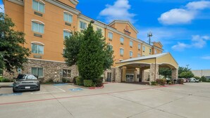 A hotel with a stone facade, a covered entrance, and a parking lot. - Comfort Suites Plano - Dallas North (Plano)