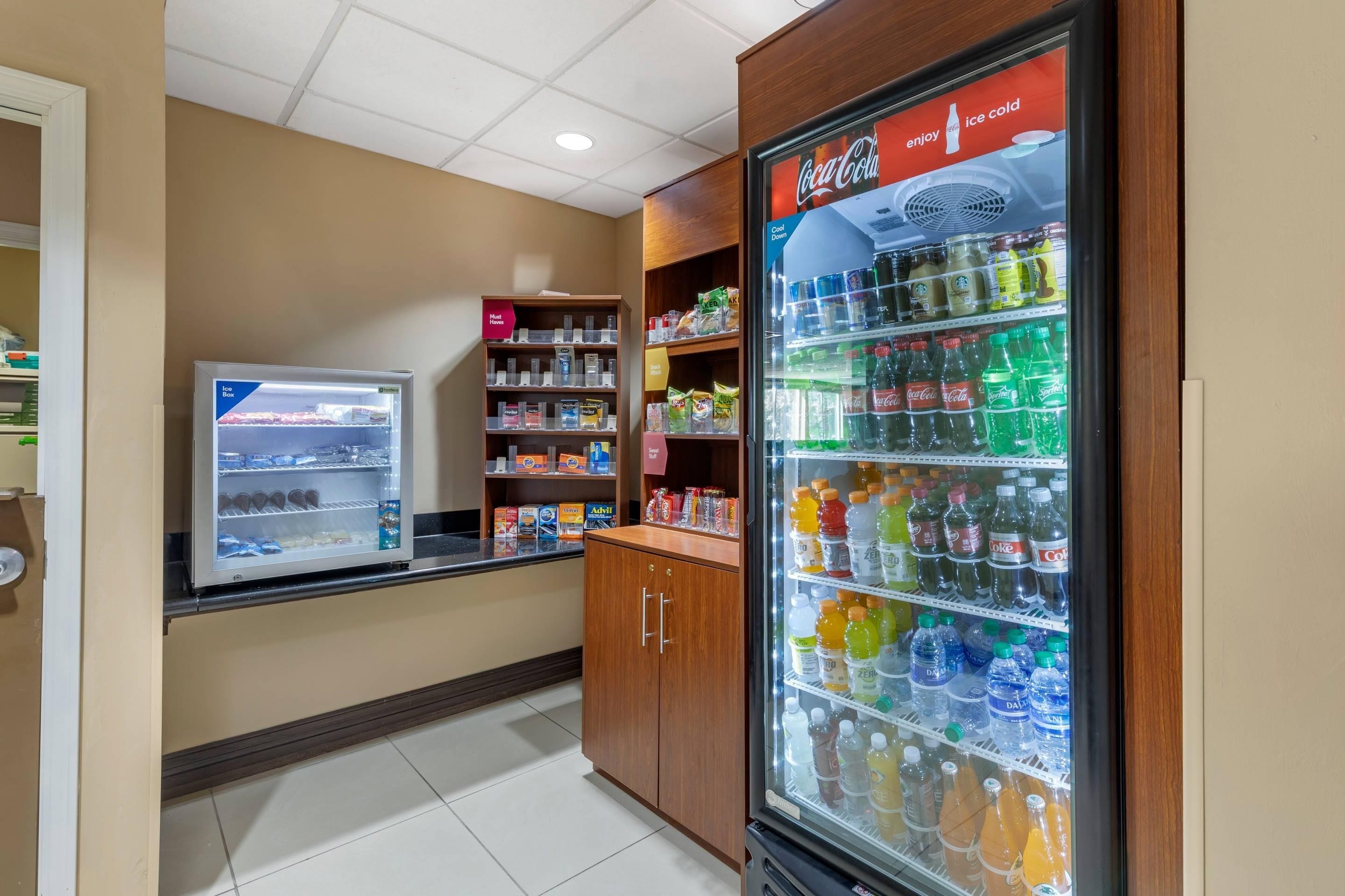 A vending machine with a variety of beverages, a refrigerated display case with snacks, and a shelf unit with packaged goods.