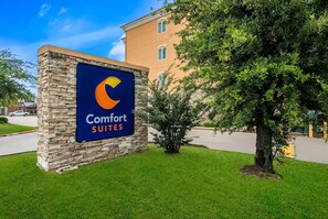 A sign for Comfort Suites hotel with a stone pillar and a tree in the foreground. - Comfort Suites Plano - Dallas North (Plano)