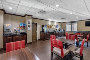 A hotel dining area with multiple tables and chairs, a coffee machine, and a refrigerator. - Comfort Suites Plano - Dallas North (Plano)