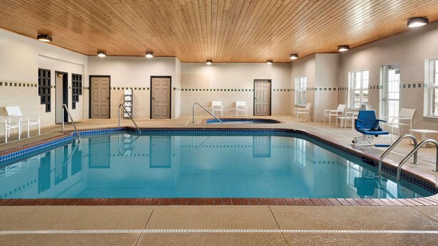 An indoor swimming pool with a wooden ceiling, tiled walls, and multiple doors. - Country Inn & Suites by Radisson, Kansas City at Village West, KS (Kansas City)