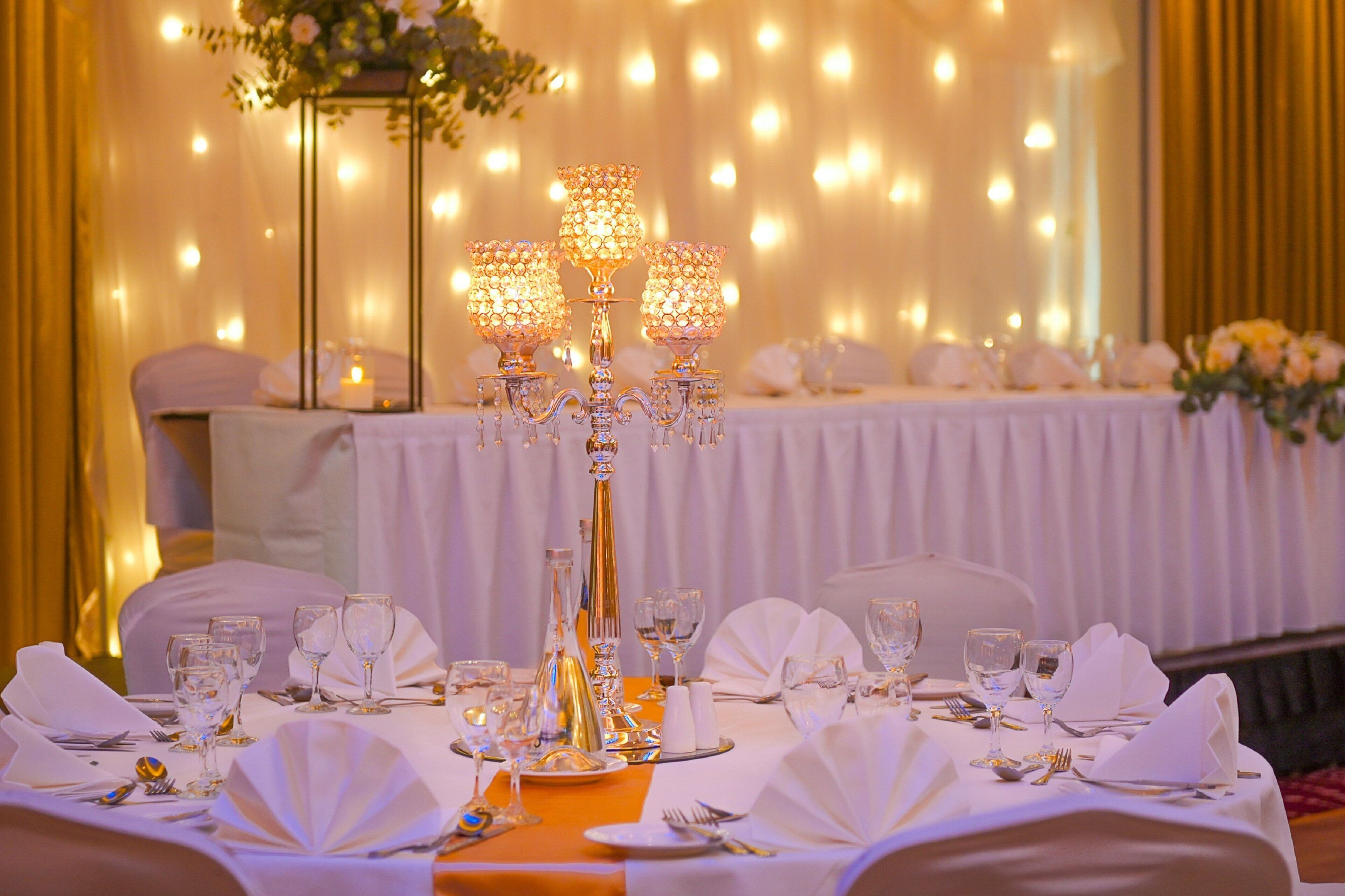 A banquet table set with white tablecloths, gold candelabras, and glassware.