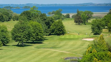 Un campo de golf con un cuerpo de agua al fondo.