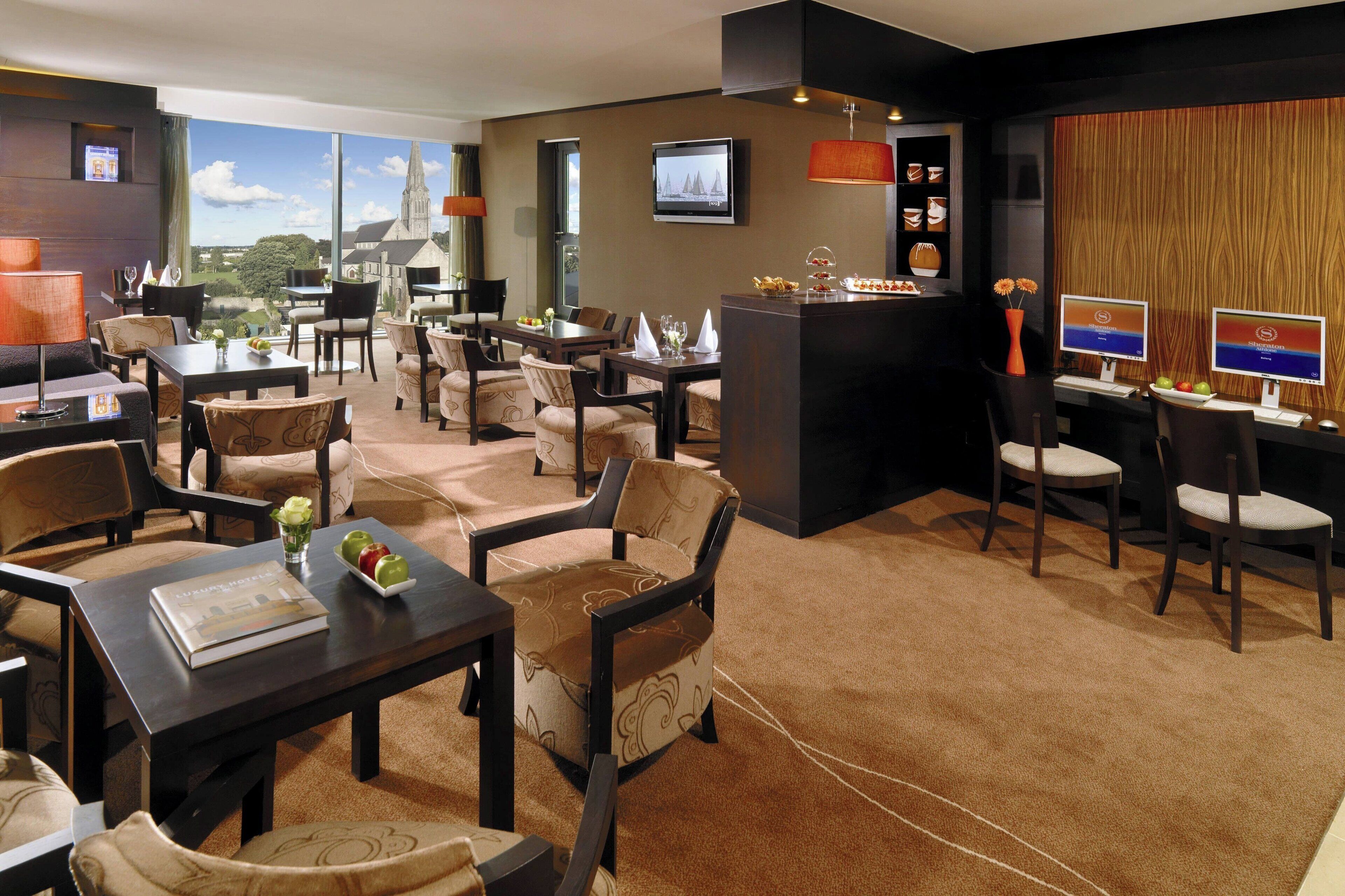 A hotel lobby with multiple seating areas, a reception desk, and a large window offering a scenic view.